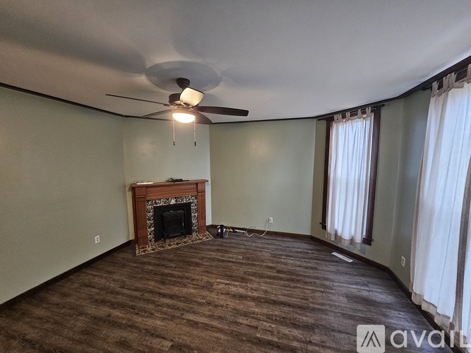 A room with a fireplace and a fan on the ceiling.