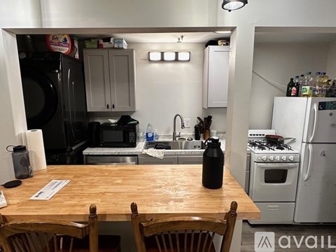 A kitchen with a wooden table and chairs in front of a refrigerator and oven.