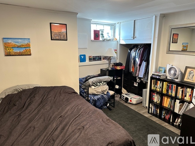 A bedroom with a bed, a bookshelf, and a painting on the wall.