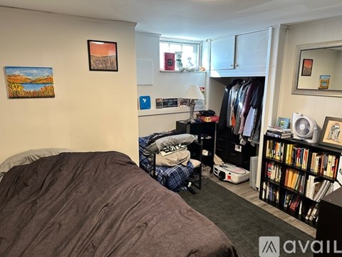 A bedroom with a bed, a bookshelf, and a painting on the wall.