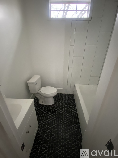 A bathroom with a toilet, sink, and black hexagonal tile flooring.