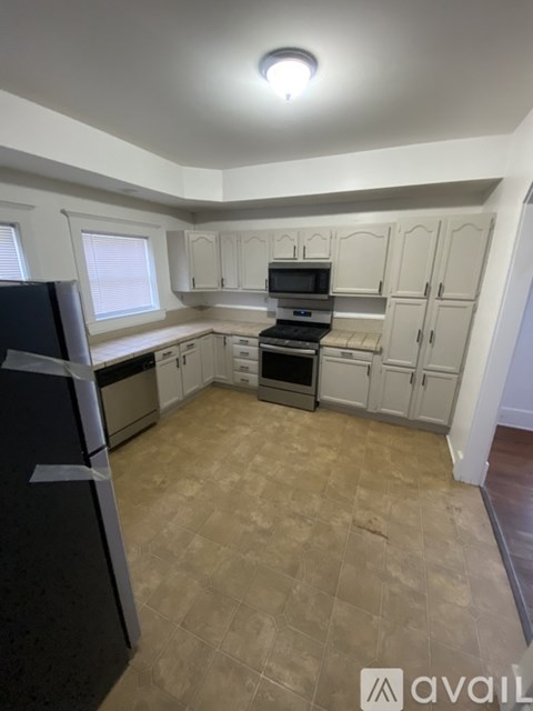 A kitchen with a black fridge, white cabinets, and a microwave.