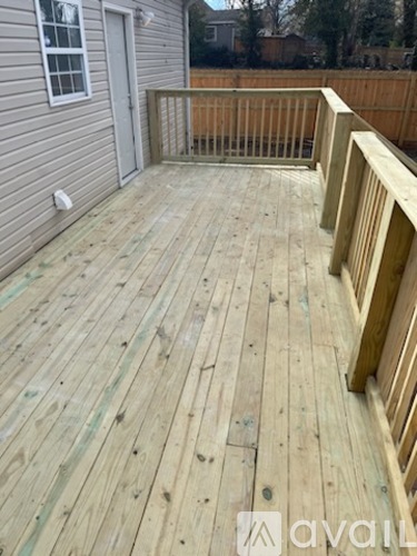 A wooden deck with a railing and a grey house in the background.