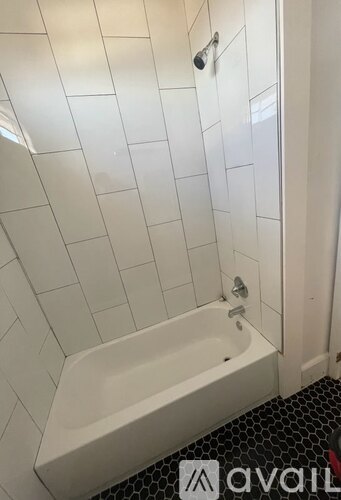 A white bathtub in a bathroom with white tiled walls.
