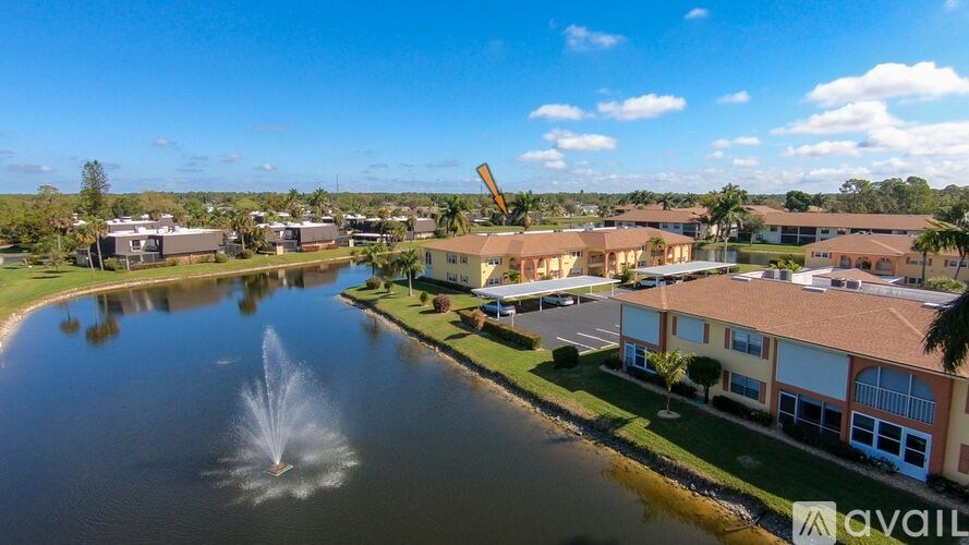 A fountain in the middle of a lake in front of a building.