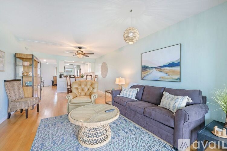 A living room with a purple couch and a painting on the wall.