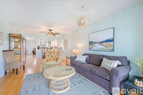 A living room with a purple couch and a painting on the wall.