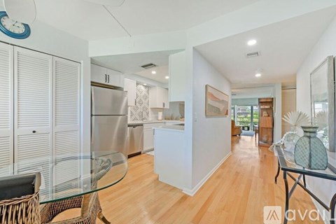 A modern kitchen with a glass table and a wicker chair.