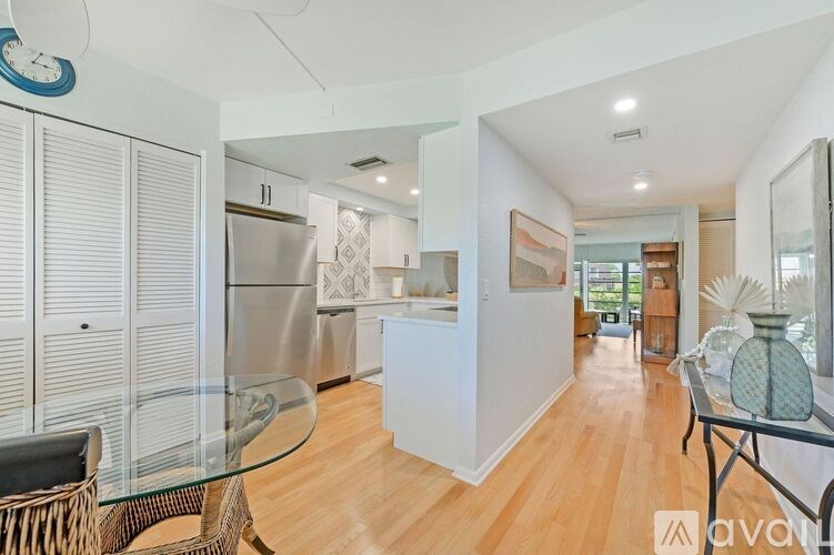 A modern kitchen with a glass table and a wicker chair.