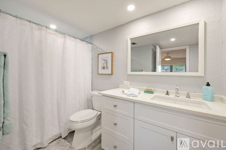 A bathroom with a toilet, sink, and mirror.