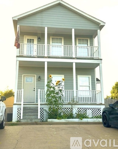 A house with a white fence and a red roof is in front of a tree.