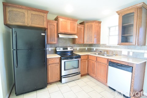 A kitchen with wooden cabinets and a black refrigerator.