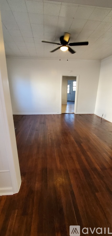A room with a ceiling fan and wooden flooring.