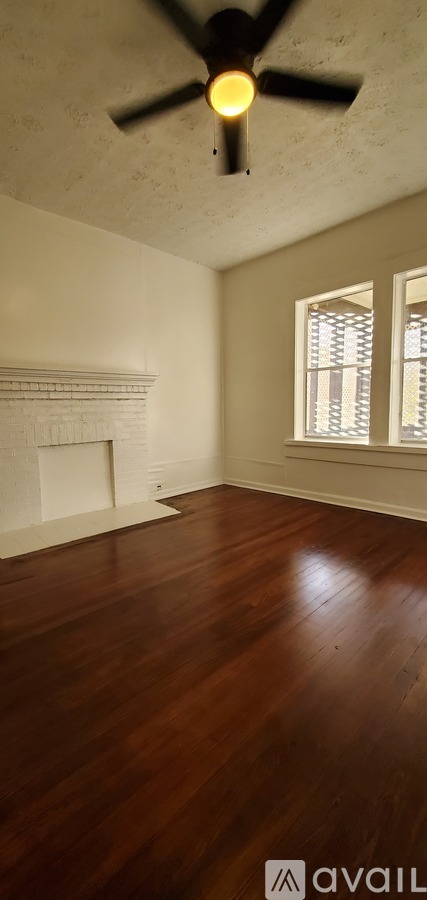 A room with a ceiling fan and a fireplace.