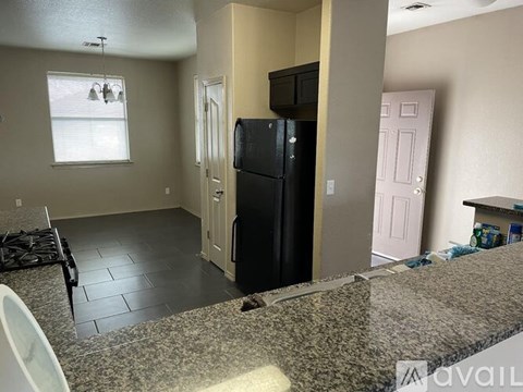 A black refrigerator in a kitchen with a pink door.