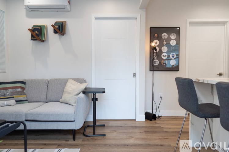 A living room with a grey couch, a small table, and a framed picture on the wall.