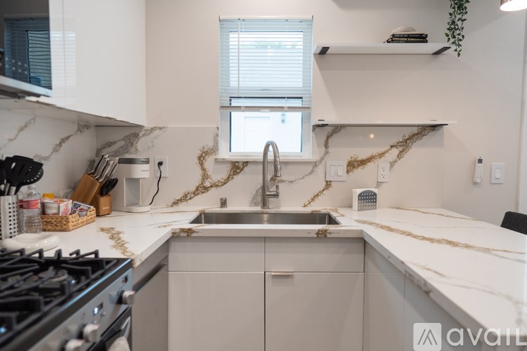 A kitchen with a marble countertop and a window above the sink.