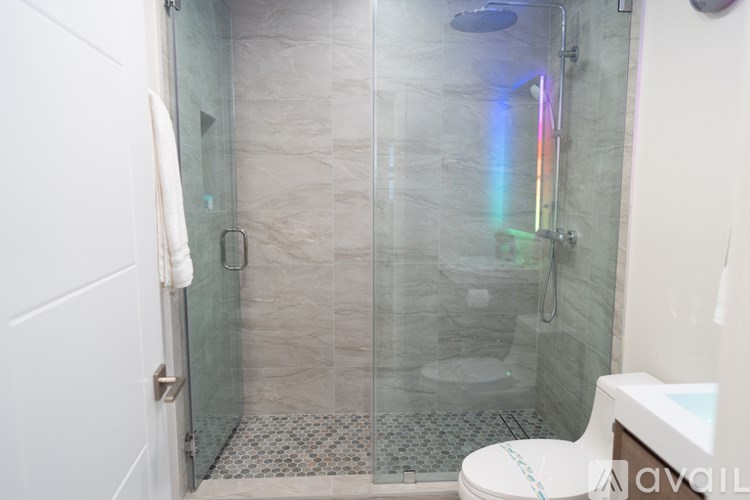 A bathroom with a glass shower door and a toilet.