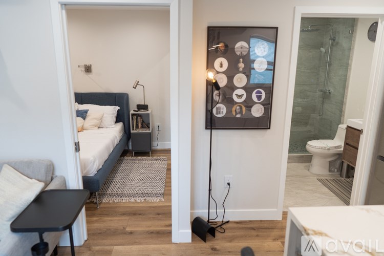 A modern bedroom with a bed, nightstand, and a wall-mounted control panel.