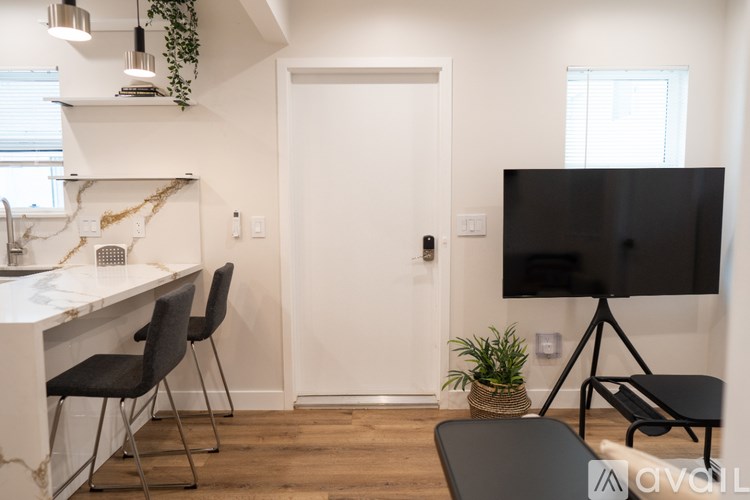A modern kitchen with a white countertop and black chairs.