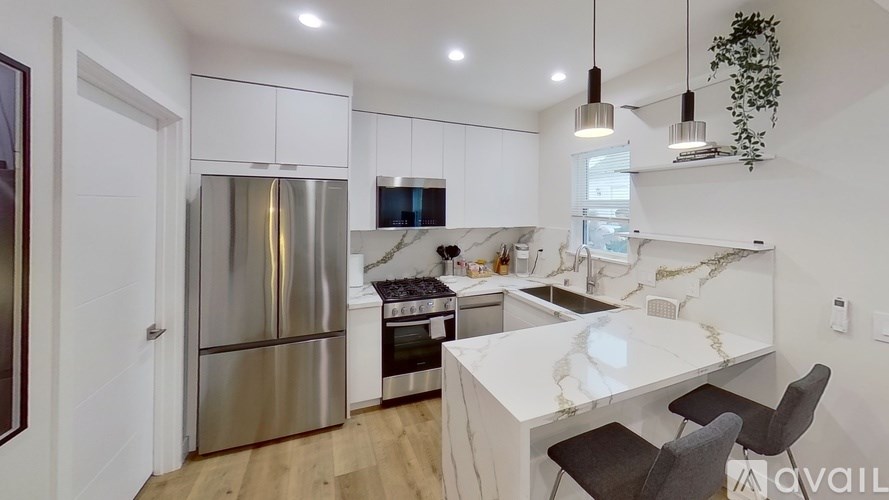 A modern kitchen with a stainless steel refrigerator and a white island.