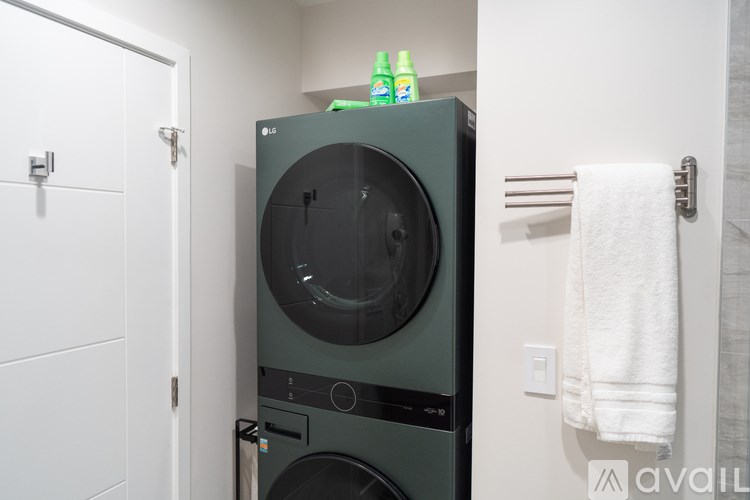 A black front loading washing machine in a white bathroom.