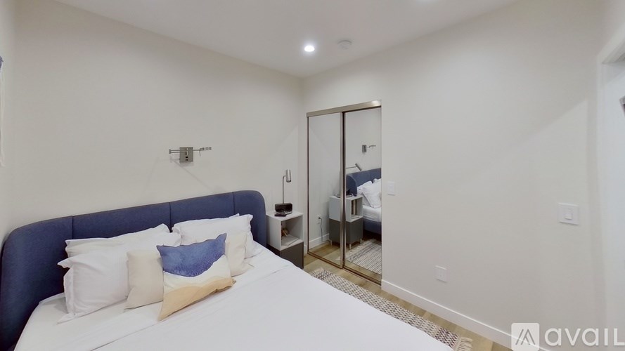 A bedroom with a bed, nightstand, and mirror.