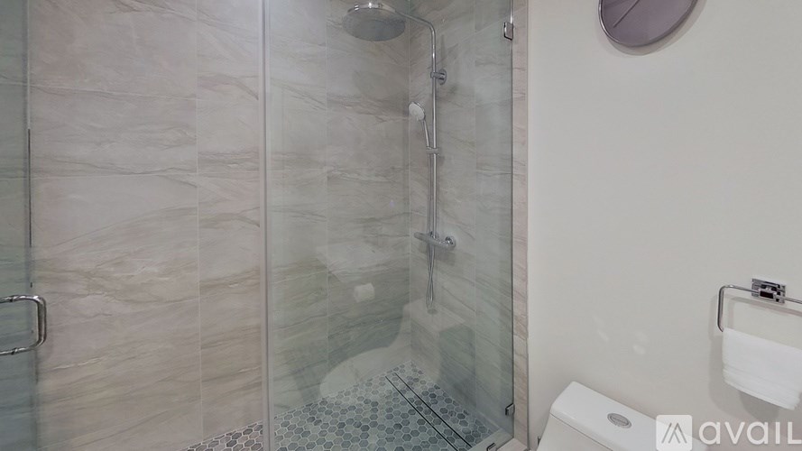 A bathroom with a glass shower door and a toilet.