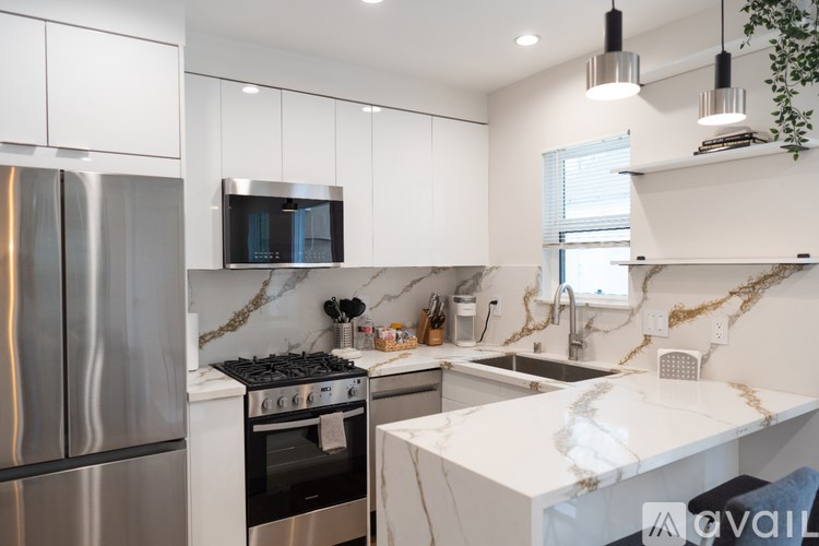 A modern kitchen with a stainless steel refrigerator and a white marble countertop.