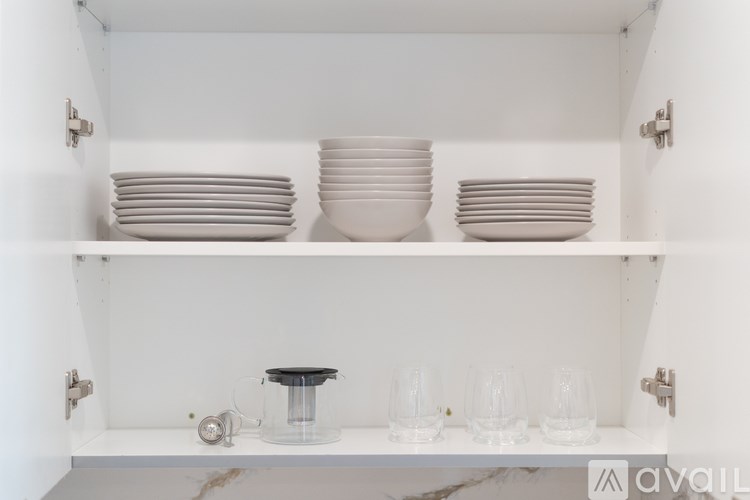 A white shelf with plates and glasses on it.