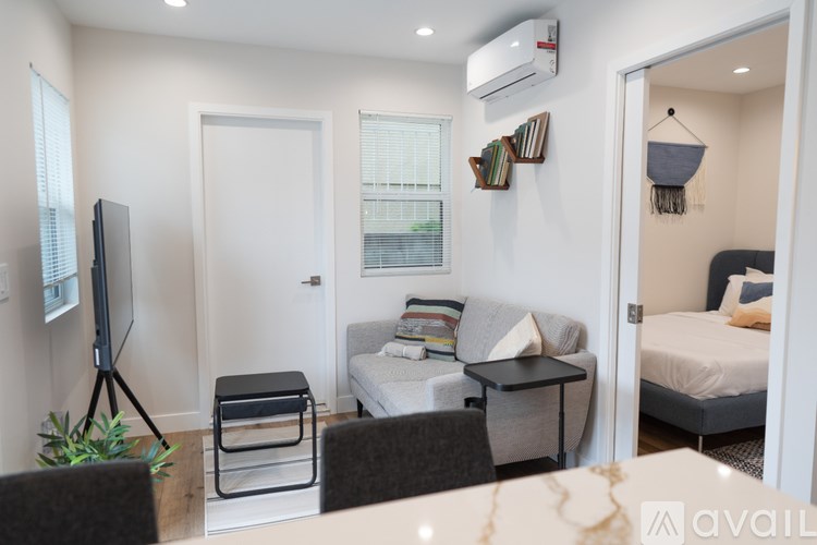 A living room with a television, a sofa, a bed, and a table.