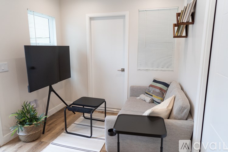 A living room with a grey couch, a black TV stand, and a plant.