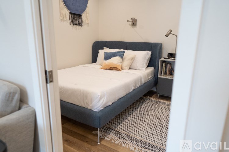 A bed with a white sheet and a blue headboard is in the image.