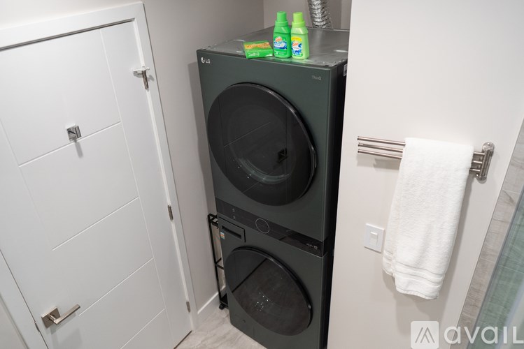 A black front loading washing machine in a small bathroom.
