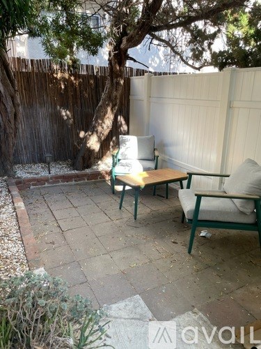 A patio with a table and chairs under a tree.