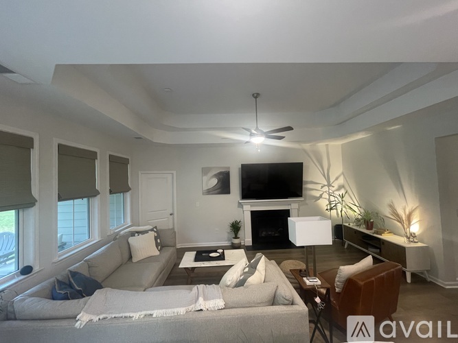 A living room with a grey couch and a television on the wall.