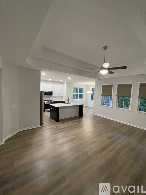 A spacious room with wooden flooring and a ceiling fan.