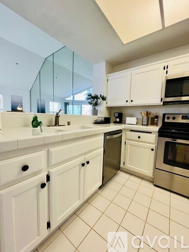 A kitchen with white cabinets and a glass backsplash.