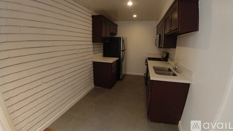 A kitchen with white walls and brown cabinets.