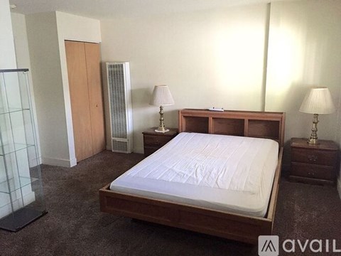 A bedroom with a bed, nightstands, and a wardrobe.