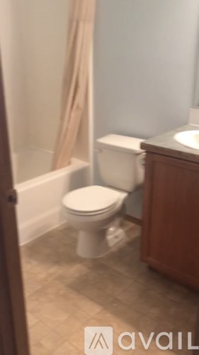 A white toilet in a bathroom with a wooden cabinet.