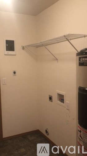 A small room with a shelf and a small white box on the wall.
