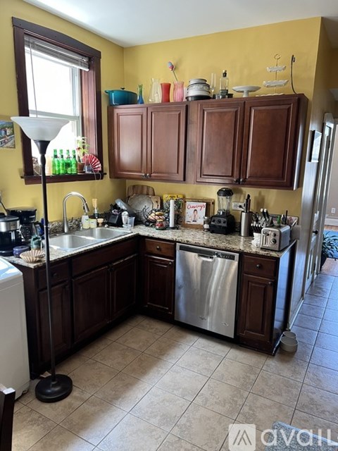 A kitchen with wooden cabinets and a yellow wall.