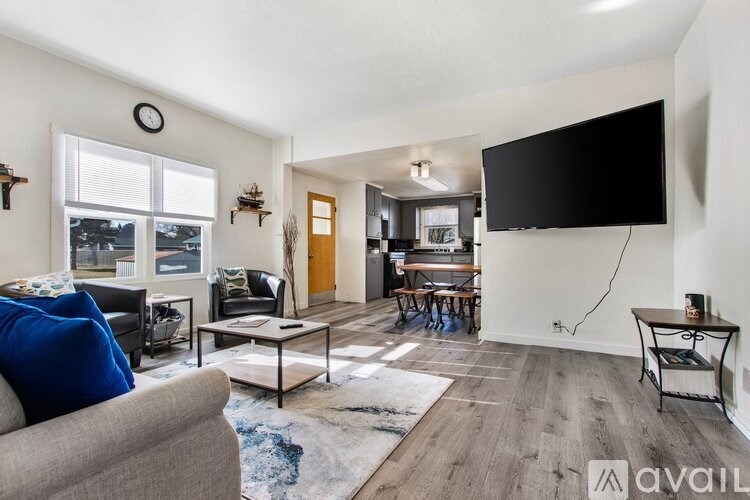 A living room with a grey couch, a black sofa, a wooden coffee table, a TV, and a rug.