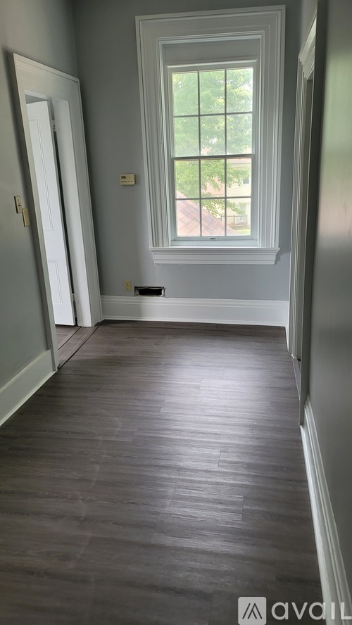 A long hallway with wood floors and a window.