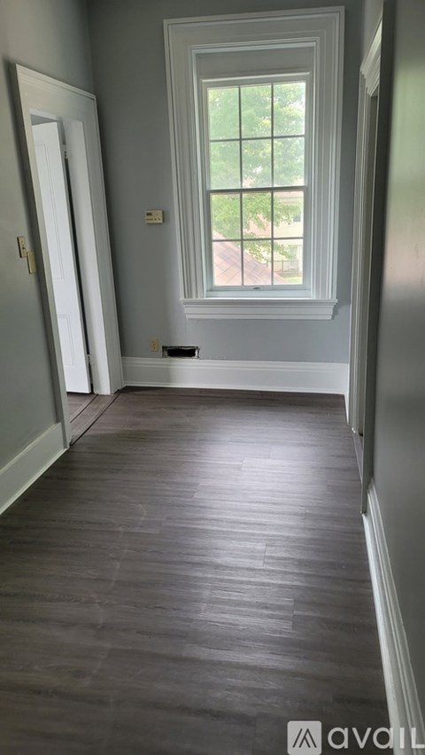 A long hallway with wood floors and a window.
