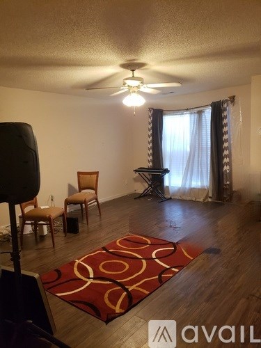 A living room with a red rug and a ceiling fan.