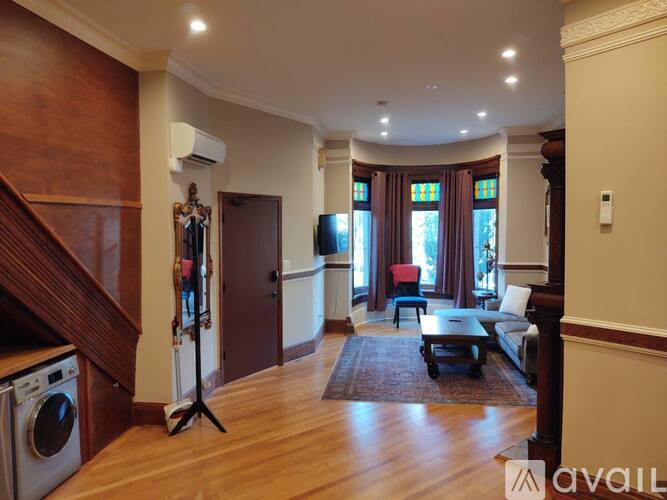 A living room with a washing machine in the corner.