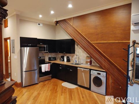 A kitchen with a stainless steel refrigerator and a washing machine.