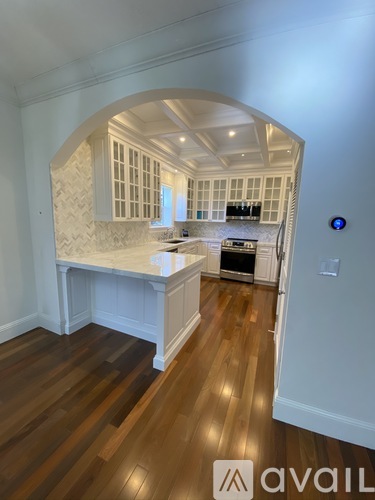 A kitchen with a white island and wooden floors.
